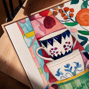 Abstract kitchen still life featuring stacked teacups with hand-painted floral designs. The watercolor technique emphasizes texture and softness, while the colorful background and botanical accents create a warm, inviting scene inspired by daily kitchen rituals.