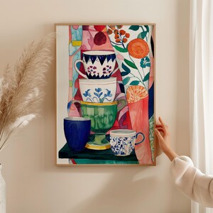 Expressive watercolor still life of stacked ceramic teacups with floral and geometric patterns. The cups are painted in blue, green, and white tones, surrounded by abstract botanical shapes and warm colors. The composition evokes comfort, creativity, and the joy of everyday tea moments.