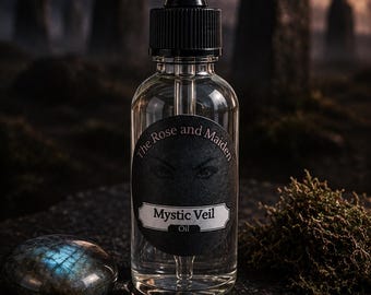 Puede incluir: Un frasco cuentagotas de vidrio transparente con tapa negra y una etiqueta que dice The Rose and Maiden Mystic Veil Oil. La etiqueta muestra un par de ojos. Junto al frasco hay una piedra azul iridiscente y un colgante de triple luna plateado.