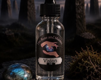 Puede incluir: Un frasco cuentagotas de vidrio transparente con tapa negra y una etiqueta que dice The Rose and Maiden Vision Oil, con una ilustración de manos sosteniendo un orbe brillante. Al lado hay una piedra azul iridiscente y un colgante de triple luna.