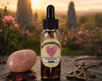 Könnte beinhalten: Eine klare Glastropfflasche mit Öl und pflanzlichen Bestandteilen, deren Etikett die Aufschrift The Rose and Maiden, True Love Oil sowie ein rosa Herz zeigt. Daneben liegen ein glatter Rosenquarzstein und ein bronzefarbener Triquetra-Anhänger.