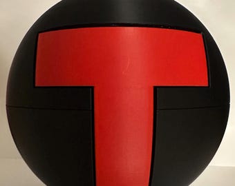 May include: A black sphere featuring a prominent red 'T' design. The 'T' is centrally positioned and stands out against the black surface. The sphere's material appears to be matte, creating a visual contrast.