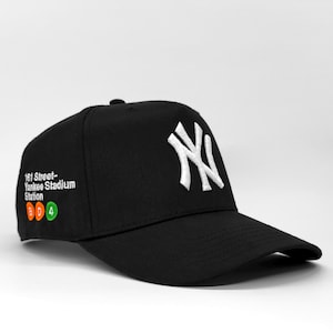 Op de afbeelding: Zwarte baseball cap met het New York Yankees logo in wit. De cap toont de tekst "161 Street-Yankee Stadium Station" en de symbolen van de B, D en 4 treinlijnen. Een klassieke, verstelbare baseball cap.