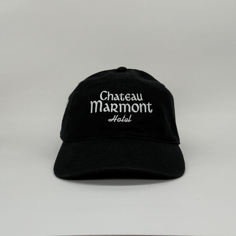 May include: Black baseball cap with the text "Chateau Marmont Hotel" embroidered in white. The cap has a curved brim and a classic six-panel design. A stylish accessory for casual wear.