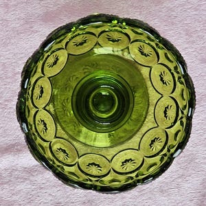 May include: A green glass pedestal bowl with a scalloped edge and a repeating pattern of stars. The bowl has a raised center base.