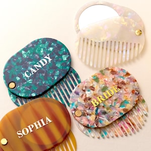 Può includere: Una collezione di pettini decorativi con specchietti allegati. I pettini presentano vari motivi colorati, tra cui verde, marrone e un design simile a coriandoli. Alcuni pettini hanno il testo "CANDY", "SOPHIA" e "BRIDE".