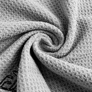 May include: Close-up of grey textured fabric with a swirling pattern. The fabric appears soft and has a woven or knitted construction, with visible texture and depth. The colour is a neutral grey.