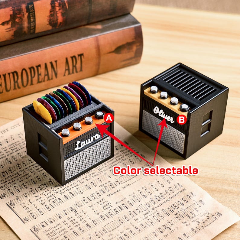 May include: Black and orange miniature amplifier-shaped storage boxes. One box has a stack of colorful guitar picks. The other box has the name "Oliver" on it. The text "Color selectable" is also visible.