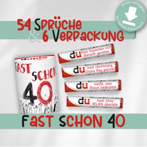 May include: A white and red Duplo container with the text "FAST SCHON 40" and "54 SPRÜCHE & 6 VERPACKUNG". Four red and white candy bars with the word "du" and German text are also visible.