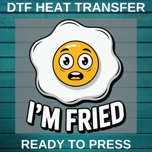 May include: DTF heat transfer design featuring a cartoon fried egg with a surprised expression. The egg has a yellow yolk, white egg white, and the text "I'M FRIED" and "READY TO PRESS" in bold white letters.