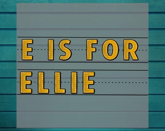 May include: A gray background with the text "E IS FOR ELLIE" in yellow letters with black outlines. The words "DTF HEAT TRANSFER" and "READY TO PRESS" are also displayed in white.