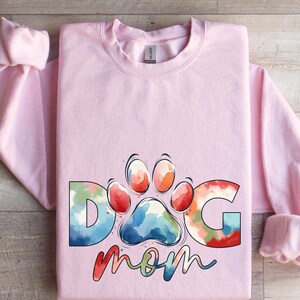 May include: Pink sweatshirt with a watercolor design of a paw print and the words "Dog Mom".