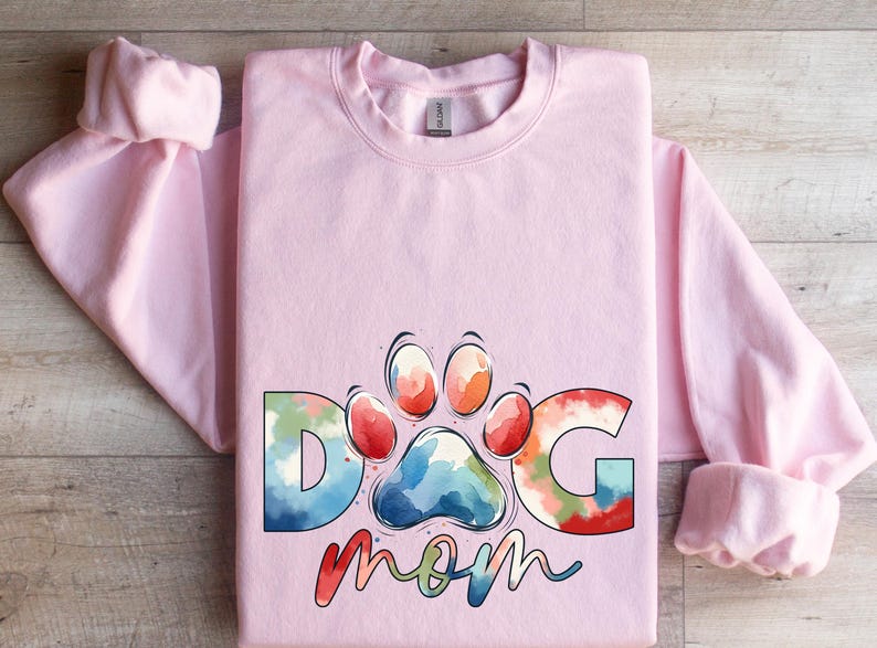 May include: Pink sweatshirt with a watercolor design of a paw print and the words "Dog Mom".