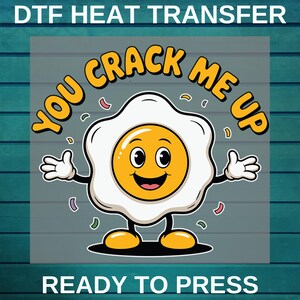 May include: A DTF heat transfer design featuring a cartoon egg with arms and legs, smiling and the text "YOU CRACK ME UP". The design includes confetti and the words "READY TO PRESS".