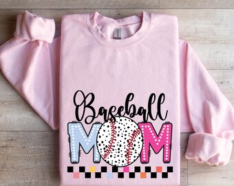 May include: Pink sweatshirt with the text "Baseball Mom" in black script. The letters are decorated with colorful polka dots and a baseball graphic is in the center.