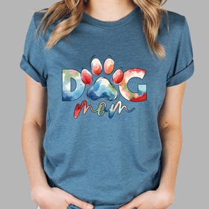 May include: A blue t-shirt with a watercolor design of a paw print and the words "DOG mom".