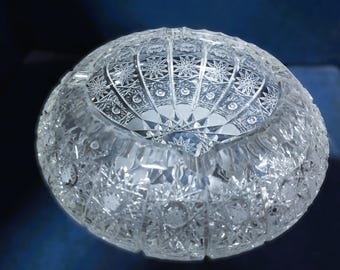 May include: A clear glass bowl with intricate cut-glass designs. The bowl has a round shape and a wide rim.