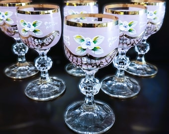May include: Set of six pink and gold hand-painted glass goblets with a floral design. The goblets have a clear glass stem and base.
