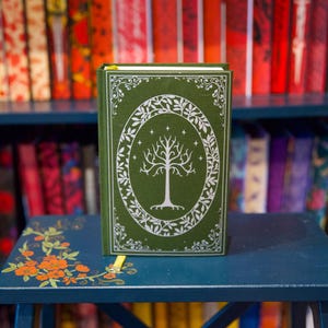 May include: A green hardcover journal with a white tree design and the words "The Lord of the Rings" on the front cover.