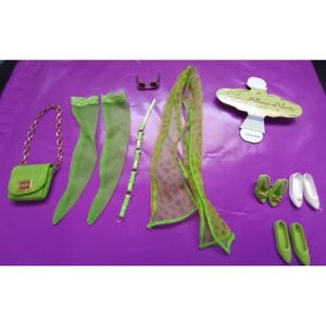 Könnte beinhalten: Ein Set aus Puppenzubehör, bestehend aus einer lindgrünen Handtasche mit Goldkette, transparenten lindgrünen Strümpfen, einem dünnen lindgrünen Gürtel, einer kleinen Brille, einem lindgrünen Schal mit Leopardenmuster, einem goldenen Etikett und drei Paar Puppenschuhen.