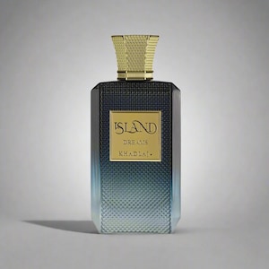 May include: A rectangular perfume bottle with a textured, gradient blue and black design. The bottle features a gold label with the words "ISLAND DREAMS KHADLAJ." The cap is gold and geometric.