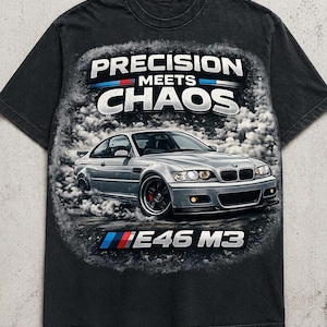 May include: Black t-shirt featuring a silver car graphic with the text "PRECISION MEETS CHAOS" above and "E46 M3" below. The car is depicted in a cloud of smoke, with red and blue accents.