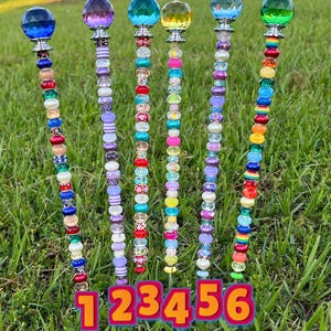 May include: Six colorful beaded garden stakes with crystal tops. The stakes are numbered 1 through 6. The beads are various colors, including purple, blue, green, yellow, and red.