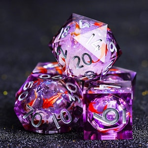 May include: A set of purple resin dice with silver numbering and red fish inclusions. The dice are in various shapes, including a twenty-sided die, a ten-sided die, and a six-sided die. The dice are designed for tabletop gaming.