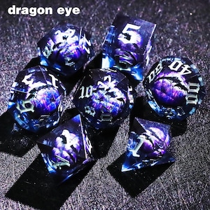 May include: Set of seven polyhedral dice with a dragon eye design. The dice are transparent with a blue and purple color scheme. The numbers are white. The text "dragon eye" is at the top of the image.