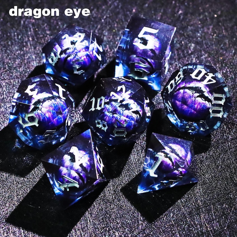 May include: Set of seven polyhedral dice with a dragon eye design. The dice are transparent with a blue and purple color scheme. The numbers are white. The text "dragon eye" is at the top of the image.