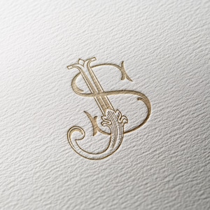 May include: Gold-coloured monogram featuring the letters "J" and "S" intertwined in an elegant, vintage style. The design includes ornate flourishes and decorative elements, set against a textured, off-white background.