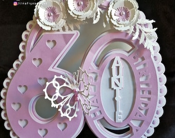 Puede incluir: Una tarjeta de papel troquelado en capas de color rosa y blanco con el número 60, una mariposa y las palabras "Feliz cumpleaños Tía".