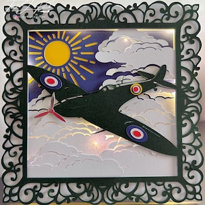 May include: A green papercraft model of a World War II era fighter plane flying through clouds with a yellow sun in the background. The plane has red, white, and blue roundels on the wings.