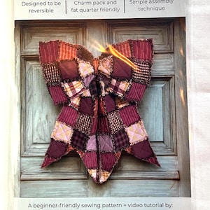 Op de afbeelding: Een naaipatroon getiteld THE BIG GIANT RAG QUILT BOW van Lindsey Grace Creates. De omslag toont een grote strik gemaakt van patchwork stoffen vierkanten in bordeaux, paars en ruitpatronen, met tekst die het beschrijft als omkeerbaar.
