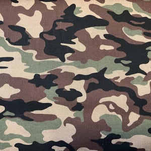 Pode incluir: Tecido camuflado com um padrão irregular em tons de castanho, verde, preto e bege. O tecido tem um aspeto texturizado, ideal para artesanato e vestuário. O design é uma estampa clássica de inspiração militar.