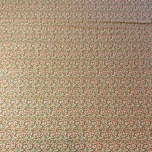 Pode incluir: Um tecido com um padrão floral repetitivo. O padrão apresenta pequenas flores rosa com centros brancos e folhas verdes, sobre um fundo castanho. O tecido tem um design denso e geral, criando uma aparência texturizada.