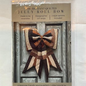 Może przedstawiać: Opakowanie wzoru szycia na pikowaną kokardę, z brązowej, beżowej i kremowej tkaniny. Tekst brzmi "The Big Giant Quilted Jelly Roll Bow". Zawiera dwie opcje stylu i jest przeznaczony do pasków o szerokości 6,35 cm.