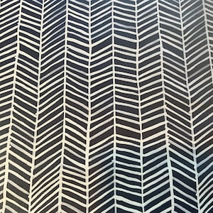 May include: A fabric with a repeating chevron pattern. The design features white, hand-drawn-style chevrons against a dark navy blue background. The pattern creates a textured, dynamic visual effect, suitable for various textile applications.