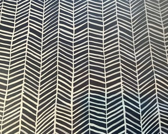 May include: A fabric with a repeating chevron pattern. The design features white, hand-drawn-style chevrons against a dark navy blue background. The pattern creates a textured, dynamic visual effect, suitable for various textile applications.