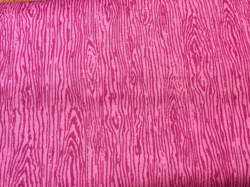 K&ouml;nnte beinhalten: Nahaufnahme eines pinkfarbenen Stoffes mit Holzmaserung. Das Design zeigt vertikale Linien in verschiedenen Rosat&ouml;nen, die einen strukturierten, nat&uuml;rlichen Eindruck erzeugen. Die Farbpalette des Stoffes wird von Rosat&ouml;nen dominiert.
