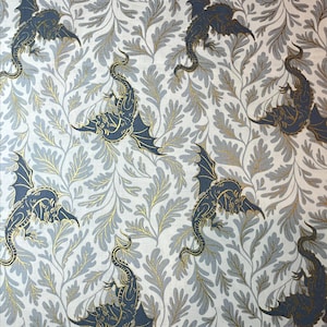 May include: A repeating pattern featuring stylized navy blue dragons with gold accents and outstretched wings. The dragons are set against a backdrop of gray and gold foliage on a white background. The design has a whimsical, fantasy theme.