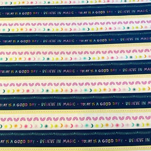 May include: Fabric with a repeating pattern of horizontal stripes in navy blue, cream, and white. The design includes text that reads "Believe in Magic" and "Today is a Good Day", along with crescent moons and arches.