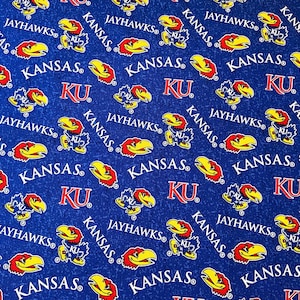 May include: Blue fabric with a repeating pattern of the word "KANSAS", the letters "KU", and the Jayhawks mascot. The mascot is a blue bird with a red head and yellow beak. The text is in white and red.
