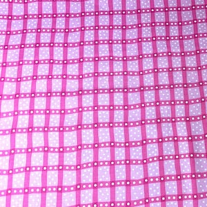 Könnte beinhalten: Nahaufnahme eines rosa-weißen Stoffes mit einem Gittermuster. Das Gitter wird durch dicke, durchgehende rosa Linien gebildet, die sich kreuzen und Quadrate bilden. In jedem Quadrat befinden sich weiße Tupfen. Der Hintergrund ist ein hellerer Rosaton.