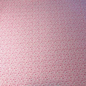 Pode incluir: Um tecido com um padrão repetitivo de pequenas flores rosa sobre um fundo branco. As flores são uniformemente espaçadas, criando uma aparência densa e texturizada. O efeito geral é delicado e feminino.