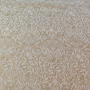 May include: Cream-colored fabric with a repeating pattern of gold dragons and flame-like shapes. The design is intricate and detailed, creating a textured appearance. The overall aesthetic is ornate and decorative.