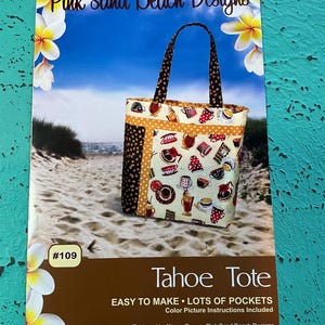 May include: A brochure for a tote bag sewing pattern, featuring a colorful tote bag with a coffee-themed print. The brochure has the text "Pink Sand Beach Designs" and "Tahoe Tote". The background shows a beach scene with flowers.
