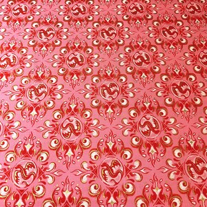 May include: Pink fabric with a repeating pattern of red dragons within circular frames, surrounded by red flames and gold accents. The design includes white scrollwork and starburst shapes, creating a decorative, ornate textile.