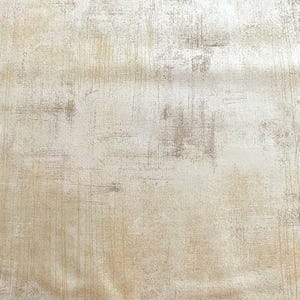 May include: A textured fabric with a distressed, aged appearance. The background is a light beige color, with darker brown and gray brushstroke-like markings. The fabric has a vintage or rustic aesthetic.
