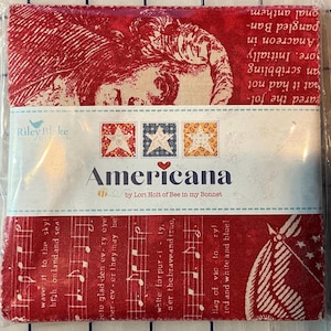 May include: A packaged fabric bundle featuring red, white, and blue Americana-themed designs. The fabric includes images of a woman's face, musical notes, and stars. The package is labeled "Americana" by Riley Blake, designed by Lori Holt.